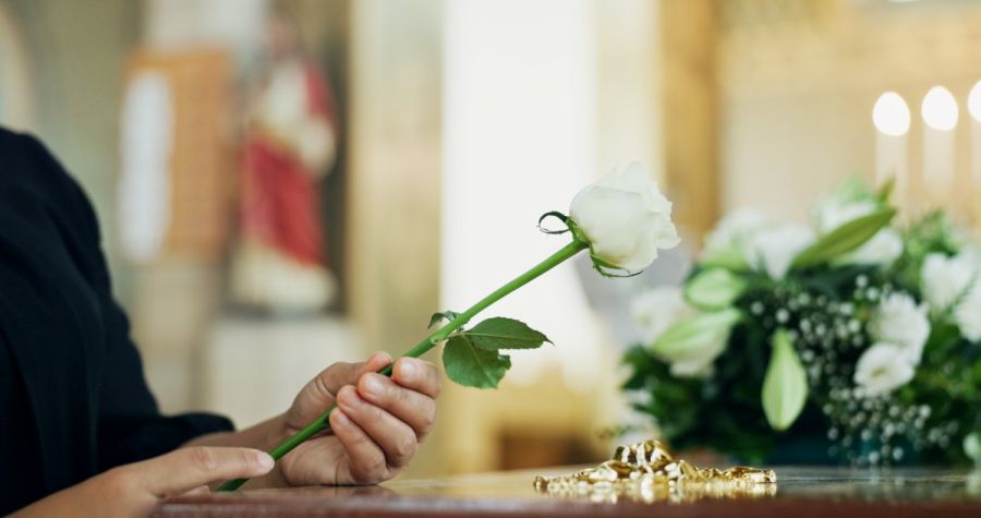 mujer con una rosa blanca sobre un ataud
